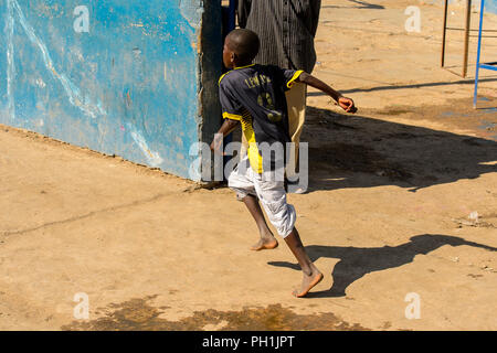 SAINT LOUIS, SENEGAL - Apr 24, 2017: Unbekannter senegalesischen kleiner Junge läuft entlang der Straße in Saint Louis, eine der größten Städte in Senegal Stockfoto