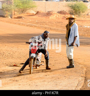 Weg zum Kalvarienberg, SENEGAL - 23.April 2017: Unbekannter senegalesischen Mann sitzt auf seinem Motorrad neben der Strasse. Noch viele Menschen im Senegal leben in pove Stockfoto