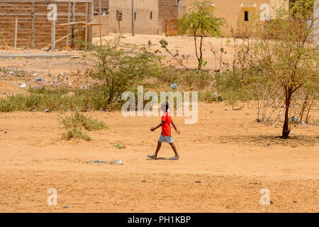 Weg zum Kalvarienberg, SENEGAL - 23.April 2017: Unbekannter senegalesischen little boy in Red Shirt und graue Shorts Spaziergänge entlang der Straße. Immer noch viele Menschen in Stockfoto