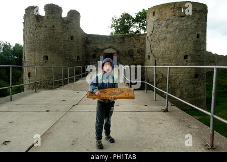 Moskau, Russland - 21. AUGUST 2018: Ein Junge steht mit einer Harfe über mittelalterliche Festung aus dem 13. Jahrhundert in Koporye. Stockfoto