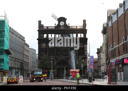 Feuerwehrmänner Spritzwasser auf brennende Glut im Inneren des Primark store in der historischen fünf Dämpfen - Geschichte Bank Gebäude im Stadtzentrum von Belfast, wo ein großbrand am Dienstag brach. Stockfoto