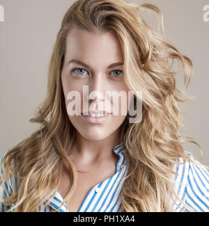 Ziemlich grauen Augen, lächelnde Frau mit einem Lächeln und sie mit ihrem blonden Haar im Wind. Stockfoto