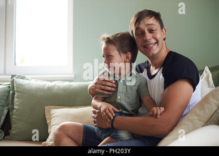 Gerne Vater mit seinem einjährigen Sohn spielen zu Hause auf dem Bett. Stockfoto