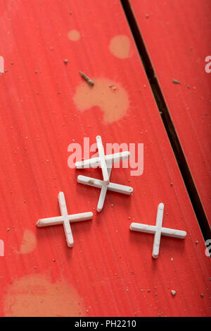 Abstandshalter aus Kunststoff für Fliesen der Wand oder Boden liegen auf rustikalen Holzfußboden in einem DIY und Sanierungskonzept. Stockfoto