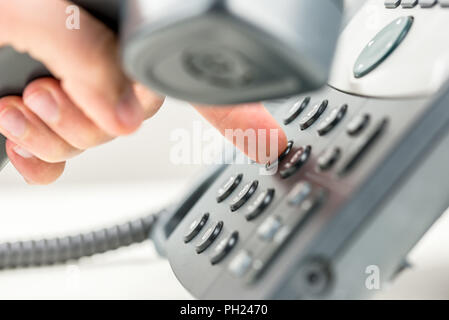 Mann heraus wählen auf ein Telefon, die den Empfänger in die Hand und drücken Sie die Nummer auf dem Tastenfeld mit seinem Finger, bis Ansicht schließen konzeptionelle von Com Stockfoto
