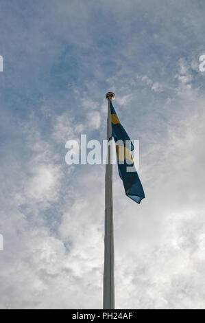 Fahnenmast mit schwedischer Flagge gegen lit Sommer Wolke Himmel Hochformat Stockfoto