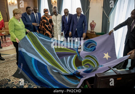 Dakar, Senegal. 29 Aug, 2018. 29.08.2018, Senegal, Dakar: die deutsche Bundeskanzlerin Angela Merkel (CDU) empfängt ein Teppich als Geschenk von Macky Sall (2. von links), Präsident der Republik Senegal. Quelle: Michael Kappeler/dpa Pool/dpa/Alamy leben Nachrichten Stockfoto