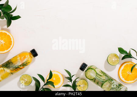 Blätter und Flasche tropischen Wasser auf weißem Hintergrund. Detox Obst infundiert Wasser, Zitrusfrüchte und Rosmarinblättern. Ansicht von oben, flach, kopieren Raum Stockfoto