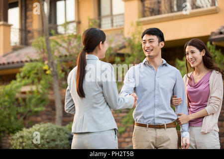 Glückliches junges Paar Hände schütteln mit Realtor Stockfoto