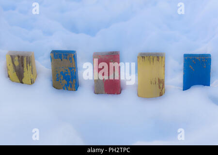 Texturierte bunt bemalten Blau, Rot, Gelb Holz- Lattenzaun Planken in tiefem Schnee, farbenfrohe Rustikale Hintergrund für Vintage Winter Wallpa Stockfoto