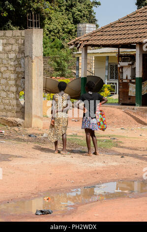 Straße nach Bissau, GUINEA B.-Mai 1, 2017: Unbekannter lokaler zwei Frauen Stehen von hinten in einem Dorf in Guinea Bissau. Immer noch viele Menschen in der COUNTR Stockfoto