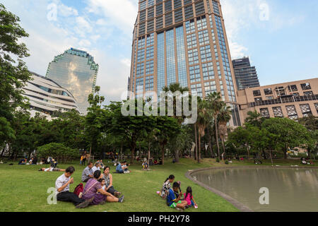 Blick auf einen Teich und viele Menschen in der Benchasiri Park und moderne Gebäude hinter dem Park in der Innenstadt von Bangkok, Thailand. Stockfoto