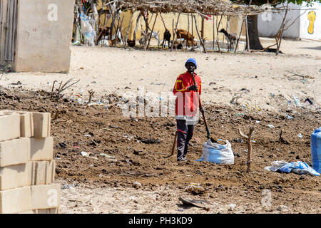 KAYAR, SENEGAL - Apr 27, 2017: Unbekannter senegalesischen Mann legt den Boden in die Tasche mit Hilfe einer Schaufel in einem schönen Dorf in der Nähe von Kayar, Sen Stockfoto