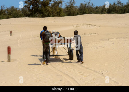 KAYAR, SENEGAL - Apr 27, 2017: Unbekannter senegalesischen zwei Männer hinter dem Wagen entlang der Straße in einem schönen Dorf in der Nähe von Kayar, Senegal Fuß Stockfoto