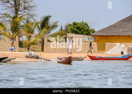 CASAMANCE FLUSS, SENEGAL - APR 29: Unbekannter senegalesische Frau trägt ein Becken auf dem Kopf an der Küste der Casamance Fluss Stockfoto