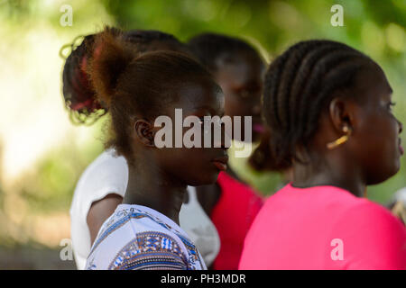 OUSSOUYE, SENEGAL - Apr 30, 2017: Unbekannter senegalesischen Mädchen in farbiges Shirt schaut etwas in den heiligen Wald in der Nähe von Kaguit Dorf Stockfoto