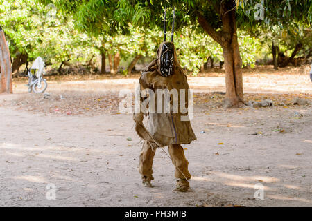 OUSSOUYE, SENEGAL - Apr 30, 2017: Unbekannter senegalesischen Mann in ein Kostüm und Maske Spaziergänge in den heiligen Wald in der Nähe von Kaguit Dorf Stockfoto