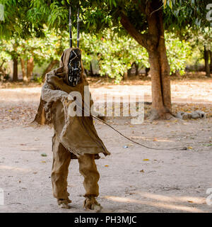 OUSSOUYE, SENEGAL - Apr 30, 2017: Unbekannter senegalesischen Mann in ein Kostüm und Maske Spaziergänge in den heiligen Wald in der Nähe von Kaguit Dorf Stockfoto