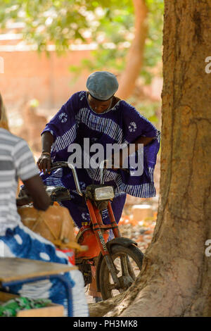 OUSSOUYE, SENEGAL - Apr 30, 2017: Unbekannter senegalesischen Mann versucht auf dem Motorrad in den heiligen Wald in der Nähe von Kaguit Dorf zu sitzen Stockfoto