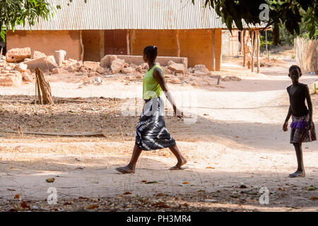 OUSSOUYE, SENEGAL - Apr 30, 2017: Unbekannter senegalesische Frau in einem T-Shirt und Rock Spaziergänge in den heiligen Wald in der Nähe von Kaguit Dorf Stockfoto