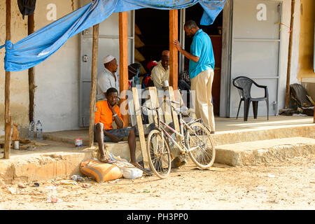 Straße nach Bissau, GUINEA B.-Mai 1, 2017: Unbekannter lokaler Männer sitzen in der Nähe der Lager in einem Dorf in Guinea Bissau. Immer noch viele Menschen im Land liv Stockfoto