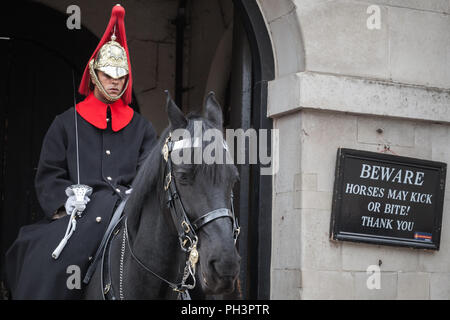 London, Großbritannien, 29. Oktober 2017: Trooper der Household Cavalry auf schwarzem Pferd steht in der Nähe von Warnung Banner auf Horse Guards von Whitehall Stockfoto