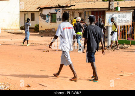 Straße nach Bissau, GUINEA B.-Mai 1, 2017: Unbekannter lokaler zwei Jungen zu Fuß von hinten in einem Dorf in Guinea Bissau. Immer noch viele Menschen im Land Stockfoto