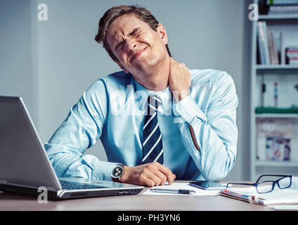 Mitarbeiter leidet unter starken Schmerzen im Hals. Foto der Mann bei der Arbeit im Büro. Medizinisches Konzept. Stockfoto