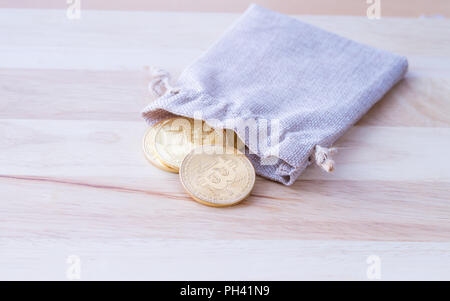 Beutel mit Gold Münzen auf Holztisch, Hintergrund, physische Version von Bitcoin, neue virtuelle Geld. Stockfoto