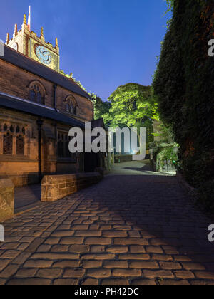 Haworth Kirche bei Nacht mit Blick auf die Straße mit Kopfsteinpflaster Pflastersteine im Vordergrund. Stockfoto