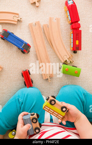 Close-up des Toddler Hände spielen mit Eisenbahn und bunten Züge. Im Innenbereich. Frühes Lernen und Entwicklung. Bildung. Transport. Stockfoto