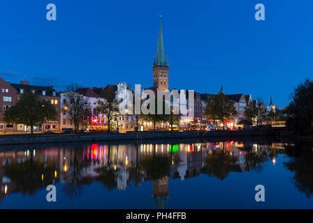 Die Kirche von St. Petri und historische Häuser spiegeln die Trave in Lübeck in der Abenddämmerung. Schleswig-Holstein, Deutschland. Stockfoto