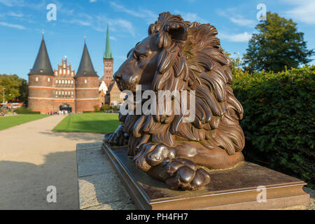 Bronze Lion Statue vor Holstein Tor (Holstentor) in Lübeck, Schleswig-Holstein, Deutschland Stockfoto