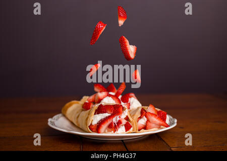 Köstliche Crêpes gefüllt mit Erdbeeren und Schlagsahne mit Erdbeeren der auf der Oberseite des Crepes. Stockfoto