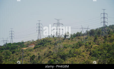 Strommasten und hohe Spannung, die durch die Berge der Cordillera. Philippinen, Luzon. Hohe Spannung Metall post, Turm. Elektrische Stromleitungen über Bäume. Stockfoto