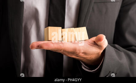Geschäftsmann Holding drei leere Holzwürfel oder Bausteine in seiner Hand für Ihren Text oder Buchstaben des Alphabets in einem konzeptionellen Bild. Stockfoto