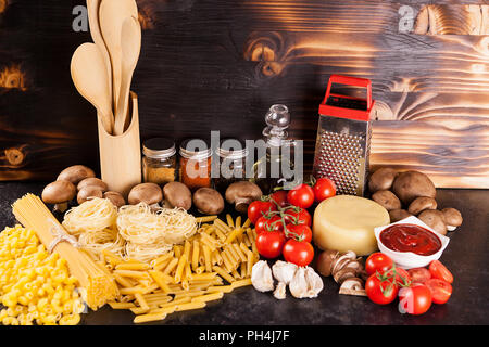 Spaghetti, Pasta und rohe Makkaroni neben einer Vielzahl von frischem Gemüse und Gewürze Stockfoto