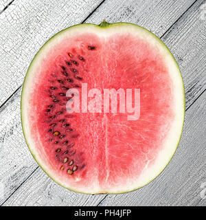 Platz Bild von geschnittenen Reifen roten Wassermelone teilweise mit und teilweise ohne Samen auf weißen alten hölzernen Tisch mit Rissen. Gesunde Ernährung und summ Stockfoto