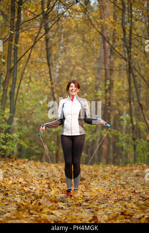 Foto der sportlichen Frau springen mit Seil im Herbst Wald Stockfoto