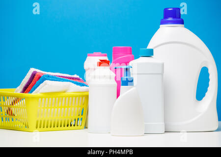 Foto Flaschen Reinigungsmittel und bunten Tücher in den Warenkorb auf blauem Hintergrund isoliert Stockfoto