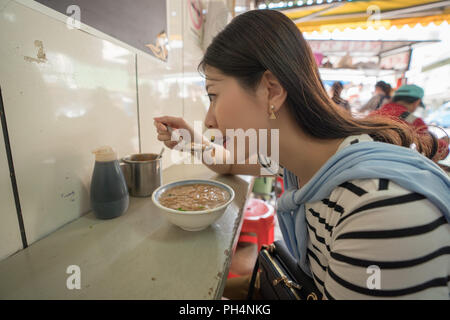 Frau Essen in traditionellen, alten Straße Markt. Lukang Tianhou Tempel Stockfoto