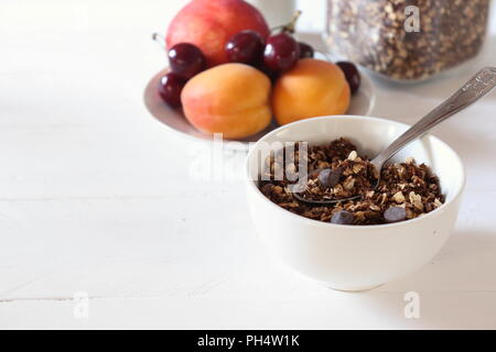 Schale hausgemachter Schokolade Müsli mit Früchten im Hintergrund (gesundes Frühstück), mit Platz für Kopie Stockfoto
