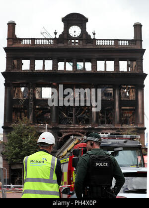 Ein Bauarbeiter und Polizeioffizier, der Blick auf den historischen 5-stöckigen Bank Gebäude im Stadtzentrum von Belfast, wo ein Großbrand im Primark Store auf Dienstag brach. Stockfoto