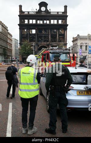 Ein Bauarbeiter und Polizeioffizier, der Blick auf den historischen 5-stöckigen Bank Gebäude im Stadtzentrum von Belfast, wo ein Großbrand im Primark Store auf Dienstag brach. Stockfoto