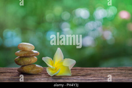 Balance Zen Steine und Gelb plumeria auf Holz mit grünen bokeh Hintergrund. Zen und Spa-Konzept. Stockfoto