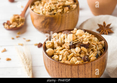 Trockene Frühstück der Hafer Flocken, Granulat und Muttern. Müsli in eine Tiefe hölzerne Platte Stockfoto