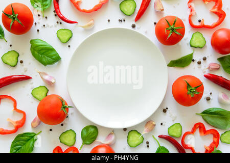 Bunter Salat Zutaten Muster aus Tomaten, Pfeffer, Chili, Knoblauch, Gurkenscheiben, Basilikum und leeren Teller auf weißem Hintergrund. Kochen conce Stockfoto