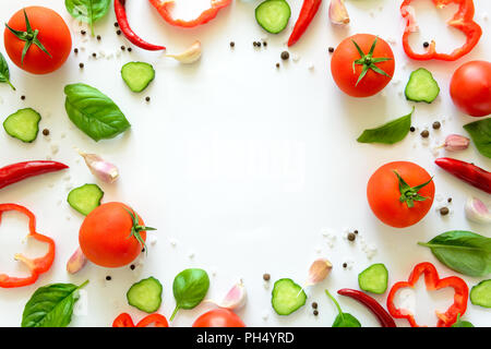 Bunter Salat Zutaten Muster aus Tomaten, Pfeffer, Chili, Knoblauch, Gurkenscheiben und Basilikum auf weißem Hintergrund. Kochen Konzept. Ansicht von oben Stockfoto