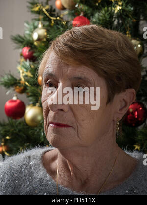 Horizontale Porträt eines traurigen ältere Frau von einem Weihnachtsbaum Stockfoto