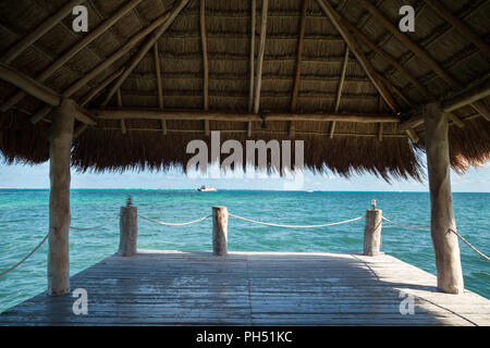 Aussicht auf die Karibik von einem Pier mit Grasdach. Stockfoto